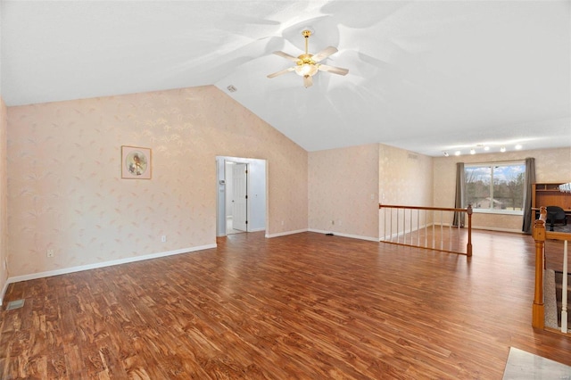 interior space with vaulted ceiling, baseboards, wallpapered walls, a ceiling fan, and wood finished floors