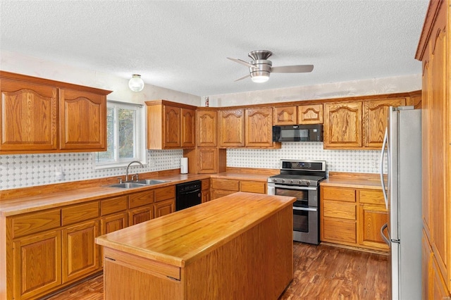 kitchen with a center island, a sink, butcher block countertops, black appliances, and dark wood-type flooring