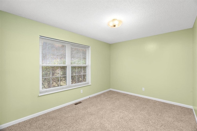 empty room with visible vents, baseboards, carpet floors, and a textured ceiling