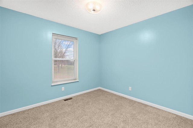 carpeted spare room with baseboards, visible vents, and a textured ceiling