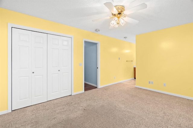 unfurnished bedroom featuring carpet, a closet, baseboards, a textured ceiling, and ceiling fan