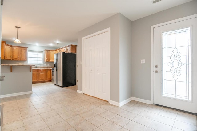 interior space with sink, kitchen peninsula, pendant lighting, light tile patterned floors, and appliances with stainless steel finishes