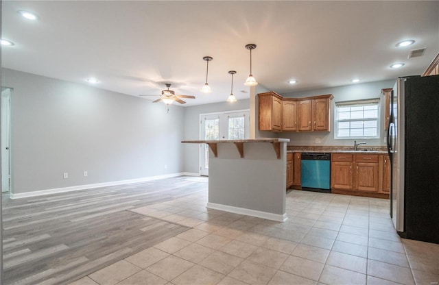 kitchen with a kitchen bar, light wood-type flooring, stainless steel appliances, ceiling fan, and pendant lighting