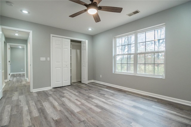 unfurnished bedroom with ceiling fan, light wood-type flooring, and a closet