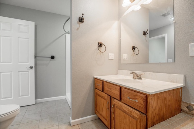 bathroom with tile patterned flooring, vanity, toilet, and walk in shower