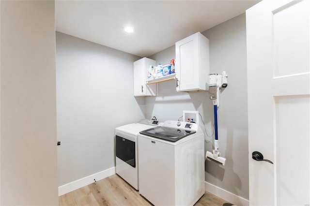 laundry room featuring washer and clothes dryer, cabinets, and light hardwood / wood-style flooring