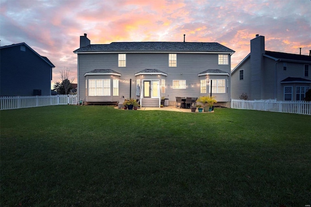 back house at dusk with a lawn and a patio area