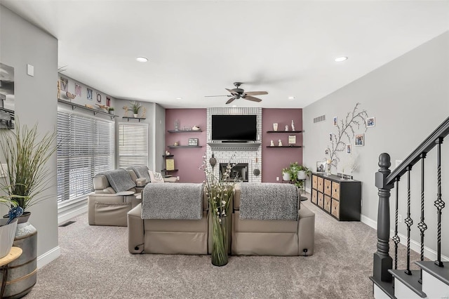 carpeted living room featuring a brick fireplace and ceiling fan