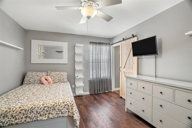 bedroom featuring ceiling fan, dark wood-type flooring, and a barn door