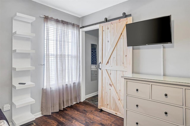 bedroom with a barn door and dark hardwood / wood-style floors