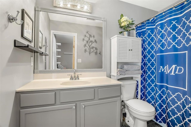 bathroom featuring toilet, a notable chandelier, and vanity