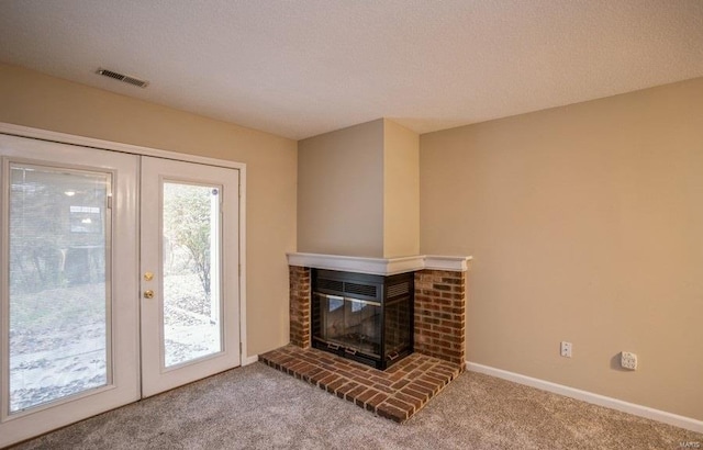 carpeted living room with a textured ceiling, a fireplace, and french doors