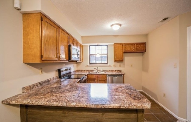 kitchen with sink, light stone countertops, a textured ceiling, kitchen peninsula, and stainless steel appliances