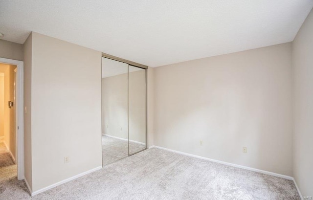 unfurnished bedroom with light carpet and a closet