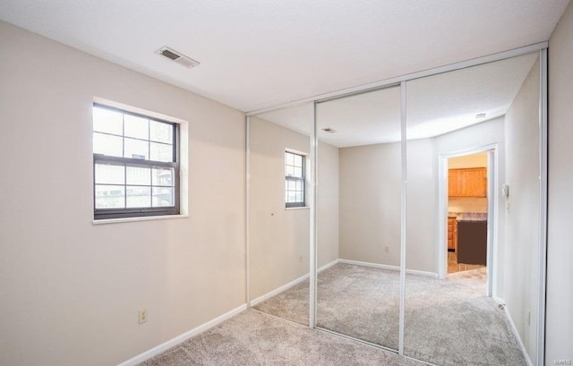 unfurnished bedroom with a closet, multiple windows, and light colored carpet