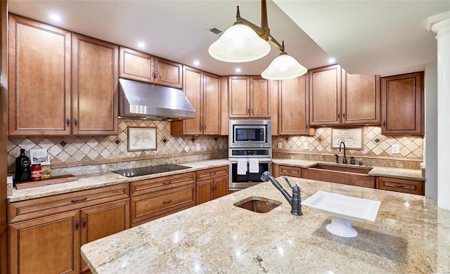 kitchen with pendant lighting, light stone countertops, backsplash, and appliances with stainless steel finishes