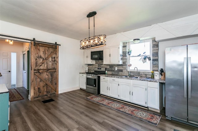 kitchen with decorative light fixtures, a barn door, white cabinetry, and stainless steel appliances