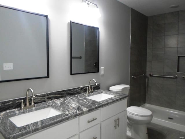 bathroom with a tile shower, vanity, and toilet