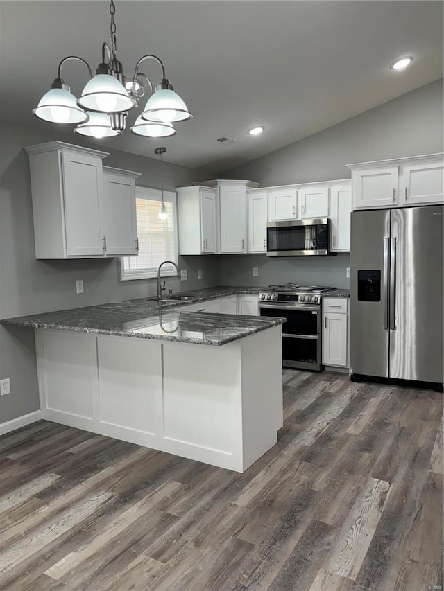 kitchen featuring white cabinets, hanging light fixtures, appliances with stainless steel finishes, and vaulted ceiling