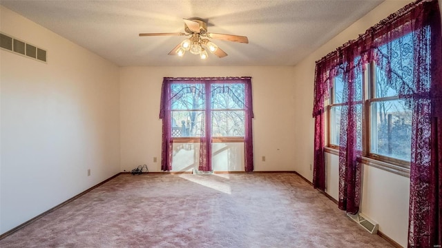 spare room with a textured ceiling, carpet floors, and ceiling fan