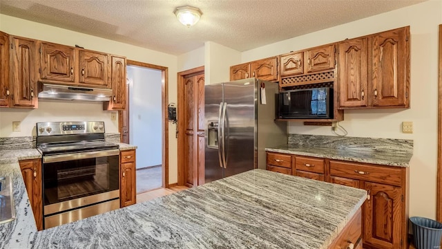 kitchen with light stone countertops, stainless steel appliances, and a textured ceiling