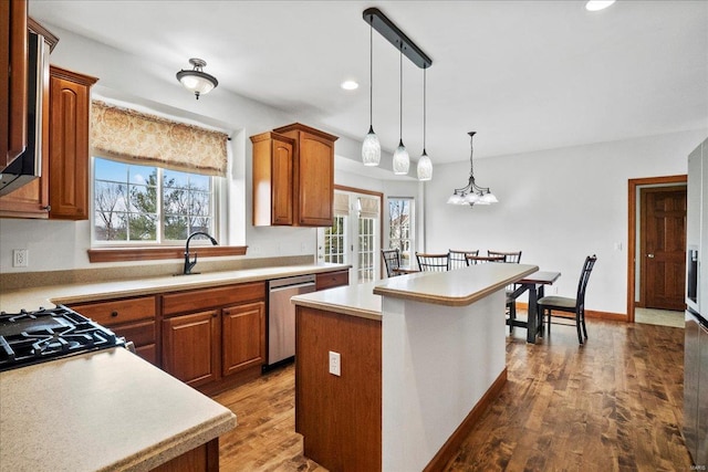 kitchen featuring stainless steel dishwasher, light countertops, wood finished floors, and a sink