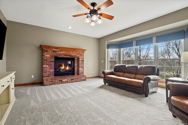 living room featuring light carpet, ceiling fan, a fireplace, and baseboards