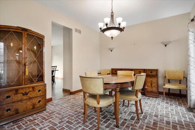 dining space featuring brick floor, visible vents, baseboards, and a chandelier