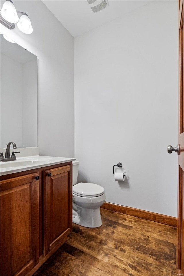 bathroom featuring vanity, wood finished floors, visible vents, baseboards, and toilet