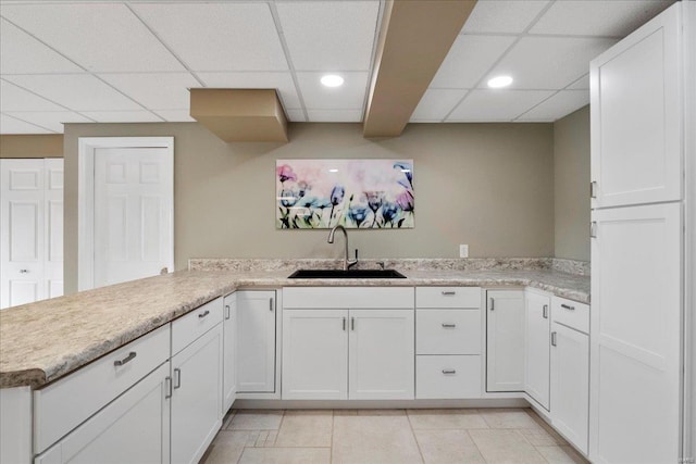 kitchen with white cabinetry, light countertops, light tile patterned floors, and a sink