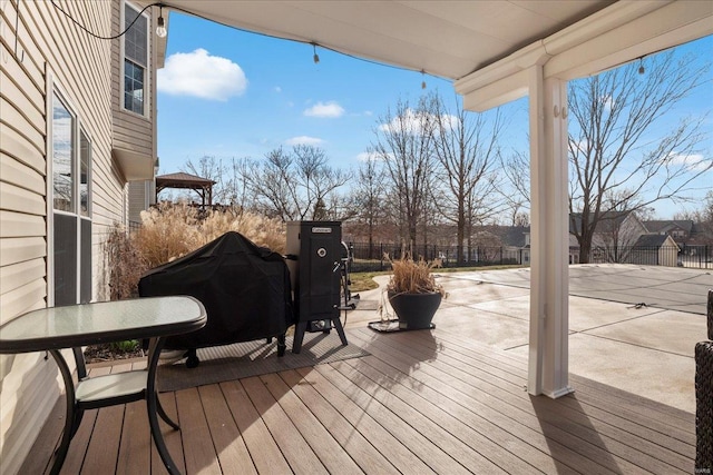 wooden deck featuring fence and a grill