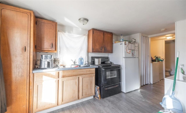 kitchen with white refrigerator, light hardwood / wood-style flooring, black range with electric stovetop, and sink