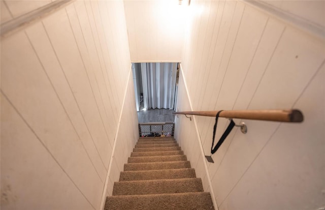 stairway featuring wood walls