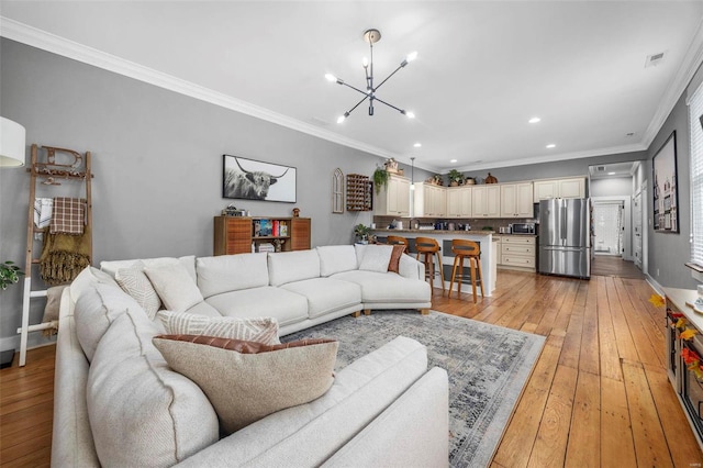 living room with an inviting chandelier, light hardwood / wood-style flooring, and crown molding