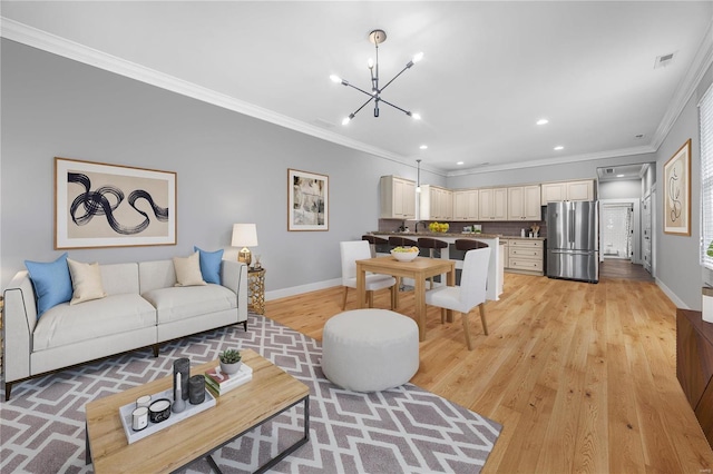 living room featuring ornamental molding, a chandelier, and light hardwood / wood-style flooring