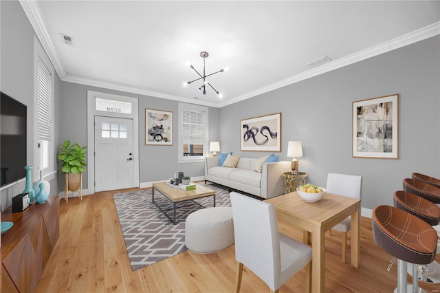 living room featuring crown molding, light wood finished floors, visible vents, a chandelier, and baseboards