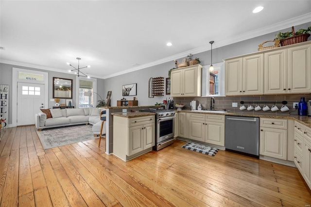 kitchen with pendant lighting, appliances with stainless steel finishes, open floor plan, a sink, and a peninsula