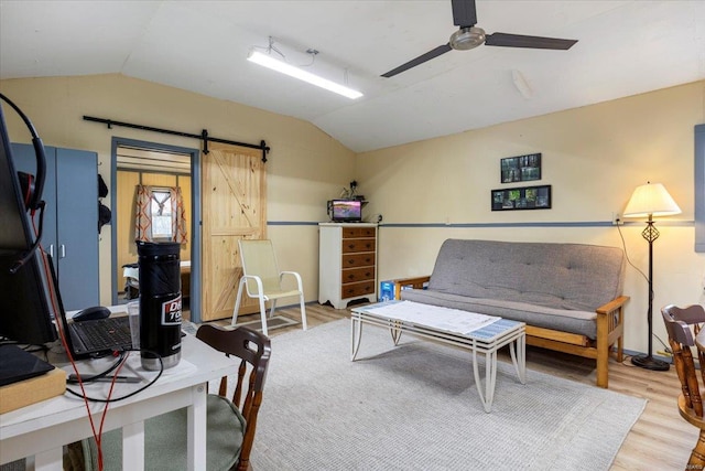 living room with a barn door, hardwood / wood-style flooring, vaulted ceiling, and ceiling fan