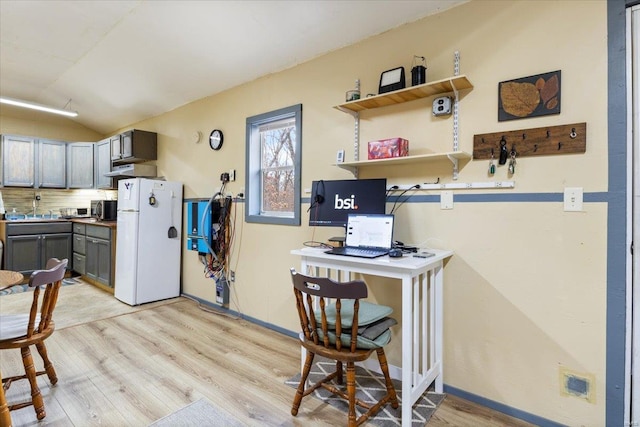 kitchen featuring gray cabinets, white fridge, vaulted ceiling, and light hardwood / wood-style floors