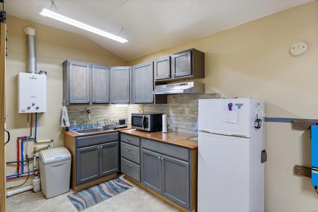 kitchen featuring white refrigerator, vaulted ceiling, gray cabinets, range hood, and tasteful backsplash