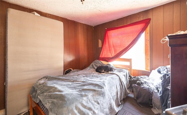 bedroom featuring a textured ceiling and wood walls