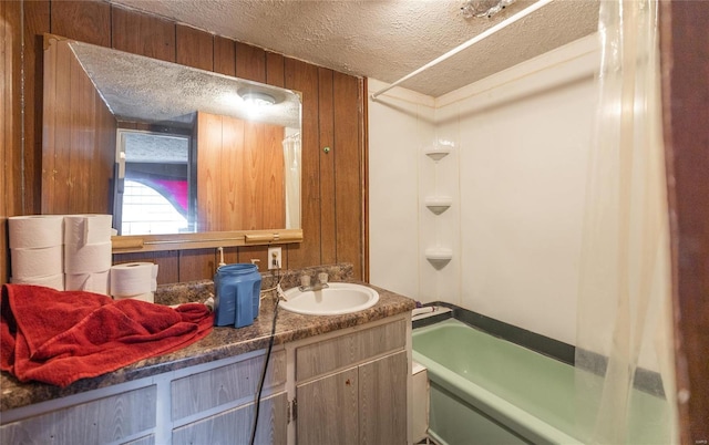 bathroom featuring shower / washtub combination, vanity, a textured ceiling, and wood walls