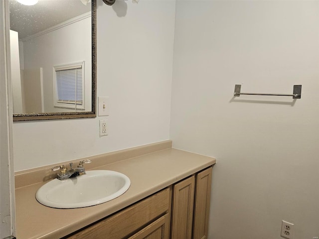 bathroom featuring vanity, ornamental molding, and a textured ceiling