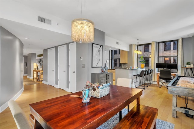 dining area featuring light hardwood / wood-style floors and a notable chandelier