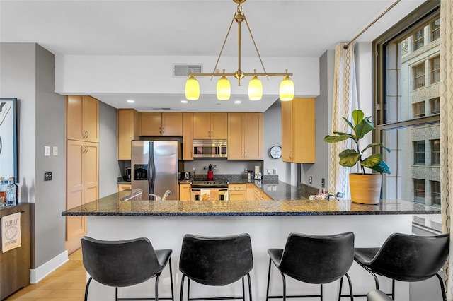 kitchen with a kitchen breakfast bar, hanging light fixtures, light hardwood / wood-style flooring, kitchen peninsula, and stainless steel appliances