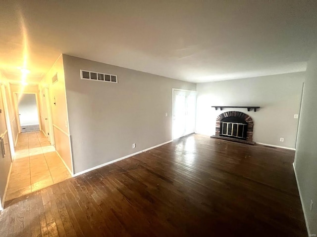 unfurnished living room featuring a brick fireplace and hardwood / wood-style flooring