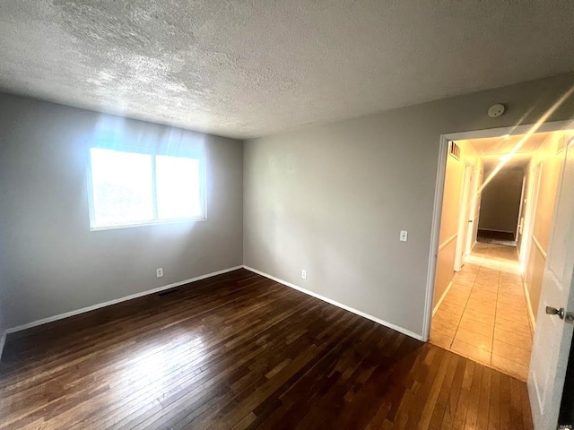 spare room featuring a textured ceiling and hardwood / wood-style flooring