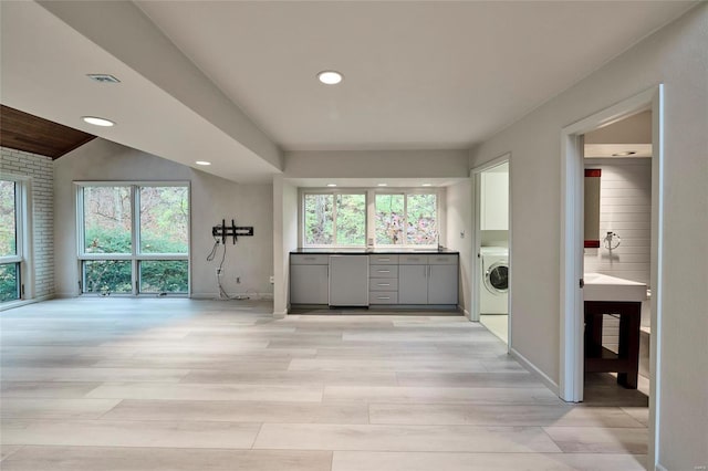 kitchen featuring stainless steel fridge, light wood-type flooring, washer / clothes dryer, and a wealth of natural light