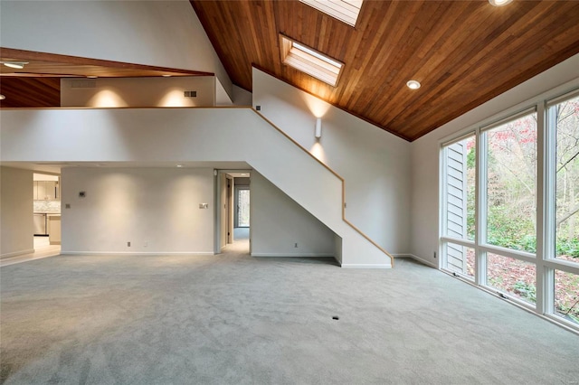 unfurnished living room with plenty of natural light, light colored carpet, wooden ceiling, and a skylight