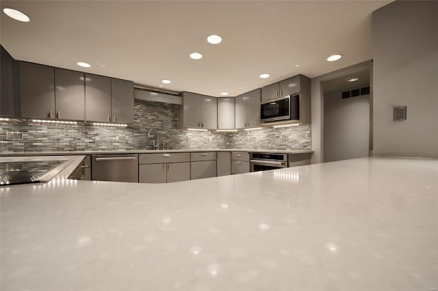 kitchen featuring gray cabinets, decorative backsplash, sink, and appliances with stainless steel finishes